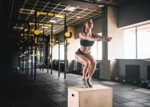 woman in black fitness gear doing box jump plyometric exercises in a gym